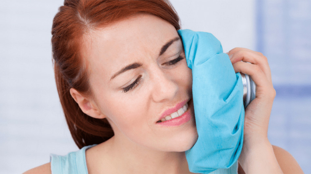 a woman using water compress after tooth extraction