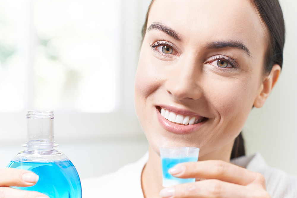 a woman who takes care of her tooth after tooth extraction using mouthwash