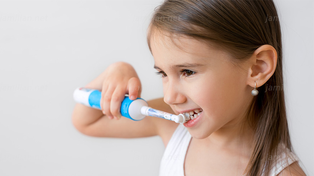 یک بچه در حال مسواک زدن دندان هاش با مسواک برقی