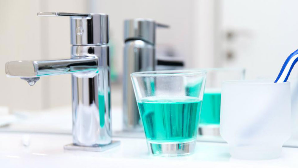 a glass of mouthwash next to the faucet