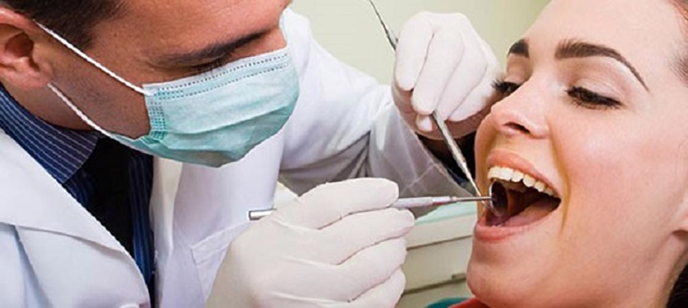خانمی که توسط متخصص ارتودنسی از نظر مرتب بودن دندان ها معاینه می شود