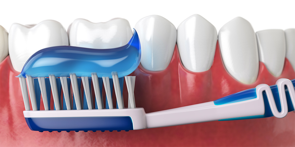 فرشاة الأسنان و معجون الأسنان بجانب أسنان الإنسان