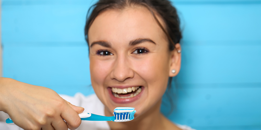 امرأة تغسل أسنانها بالفرشاة للحفاظ على نظافة الفم