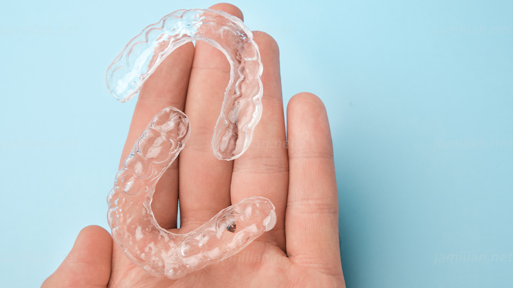 close up mans hand holding removable retainer