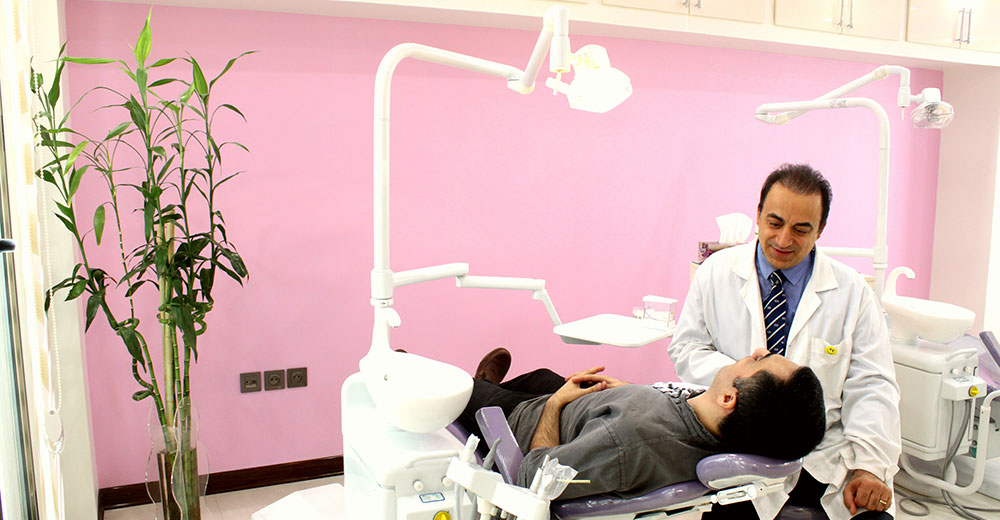 أخصائي تقويم الأسنان الدكتور جميليان الذي يقوم بفحص مريض في وحدة الأسنان في عيادته.