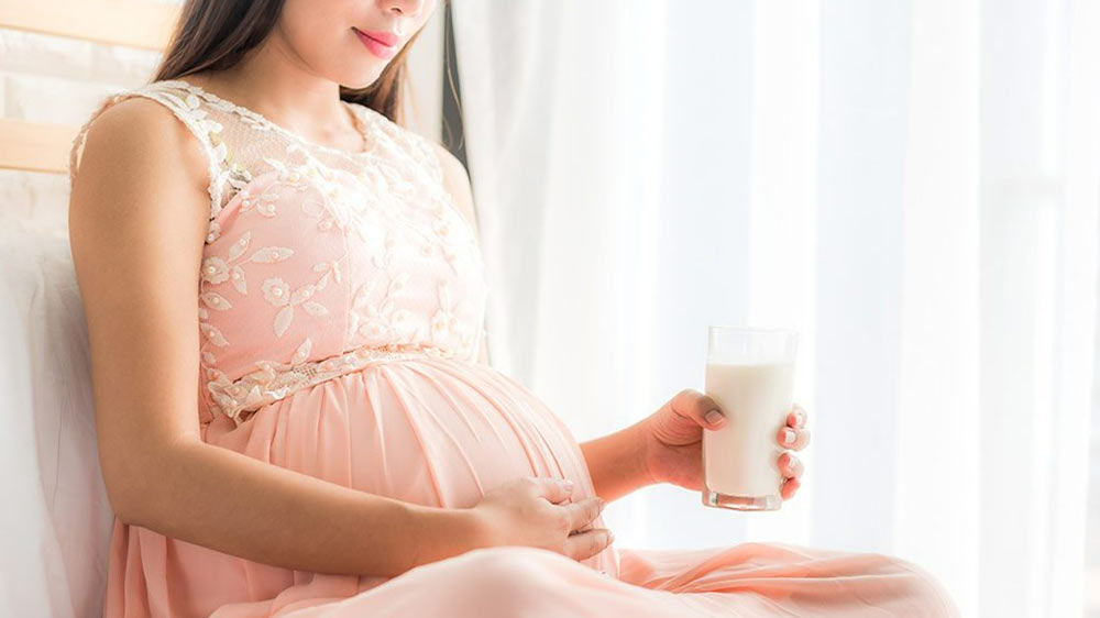 خانم بارداری که یک لیوان شیر در دست دارد