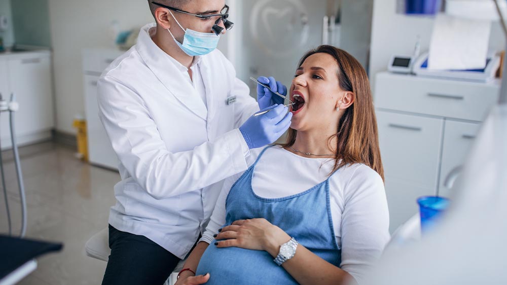 دندانپزشک در کلینیک دندانپزشکی در حال پرکردن دندان خانم حامله