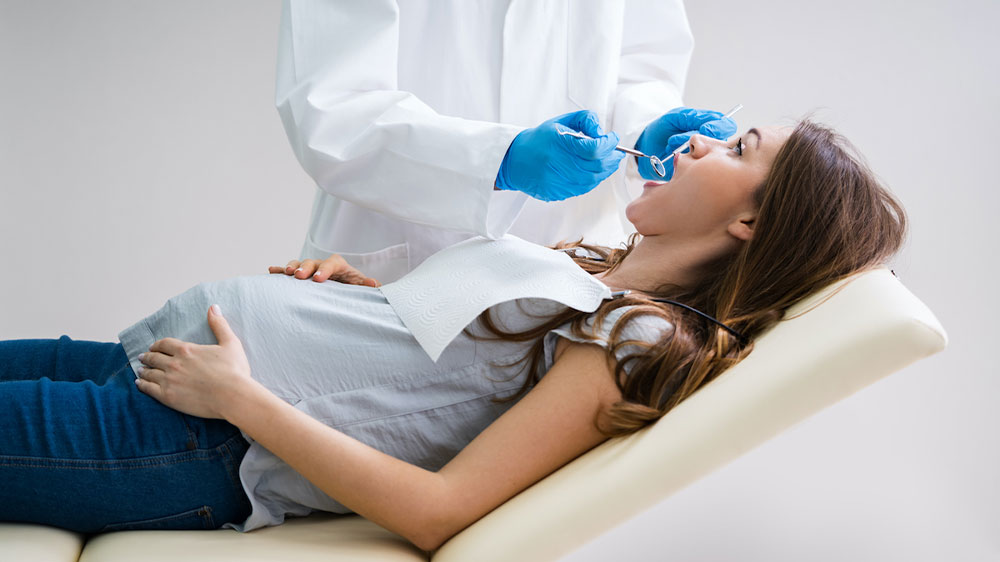 دندانپزشک در حال معاینه وضعیت دندان های خانم باردار
