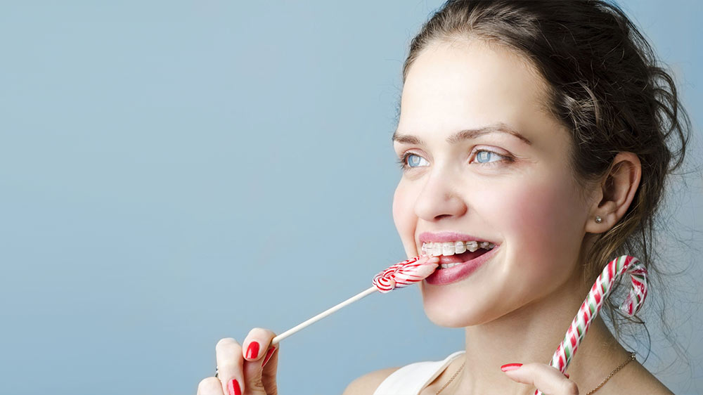 woman with blue eyes and orthodontics eating candy